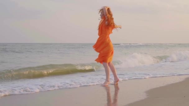 无忧无虑的女人在海边的夕阳上跳舞。女孩旋转。日落时分的女性气质。慢动作. — 图库视频影像