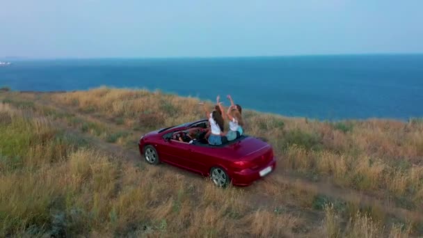 Letecký pohled. Mladé ženy se baví v kabrioletu na pobřeží. — Stock video