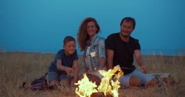 Oğlu ve ailesi lokumları çubukla kızartıyor. Akşam ları sahilde aile kampı. Bir aile.