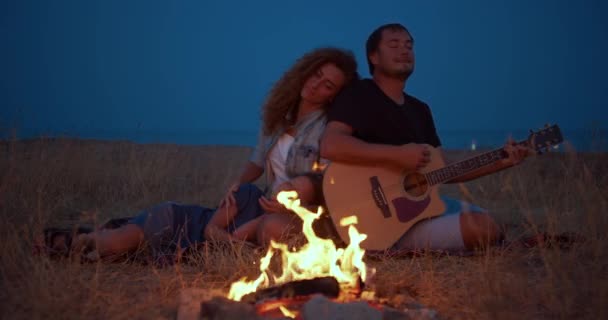 Daddy speelt gitaar, moeder met zoon geniet terwijl u ontspant op familie picknick in de buurt van vreugdevuur. Close-up. — Stockvideo