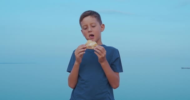 El chico está comiendo pizza al aire libre. Chico sonriente con una deliciosa pizza . — Vídeos de Stock