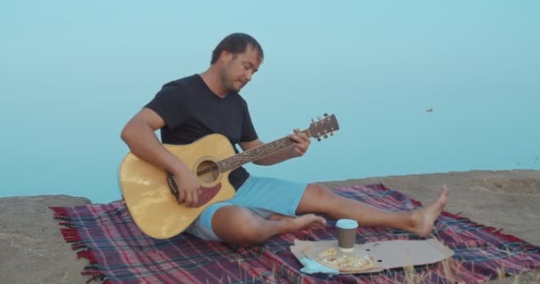 De man speelt de gitaar en zingen op het strand. — Stockvideo