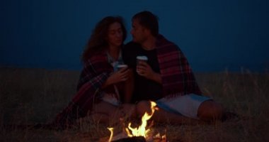 Romantik çift geceleri bir kamp ateşi etrafında oturan.