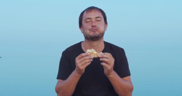 남자는 앉아서 야외에서 피자를 먹는다. 근접 촬영. — 비디오