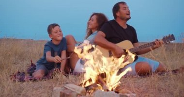 Aile akşam yuvarlak parlak bir şenlik ateşi açık oturan.