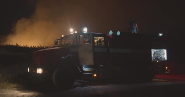 Camion dei pompieri con luci accese. Camion dei pompieri sullo sfondo di erba bruciata sul campo durante gli incendi boschivi. Salvataggio e prevenzione delle catastrofi naturali . — Video Stock