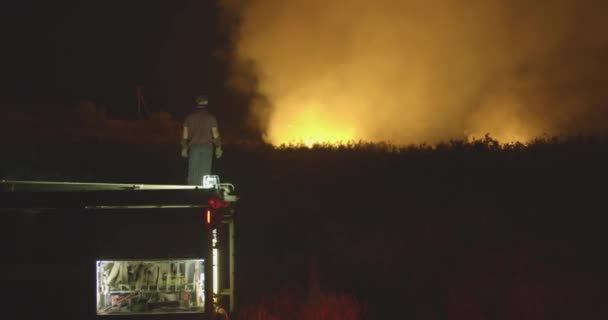 Brandweerwagen op de achtergrond van het verbranden van gras op veld tijdens bosbrand. Redding en preventie van natuurrampen. — Stockvideo