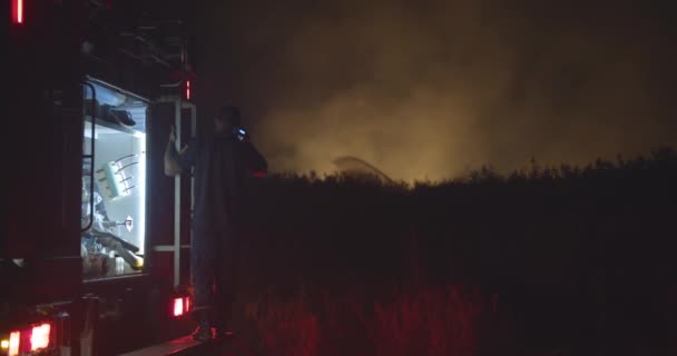 Brandbil med blinkande ljus på bakgrund brinnande fält. — Stockvideo