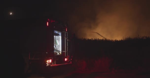 Brandbil med blinkande ljus på bakgrund brinnande fält. — Stockvideo