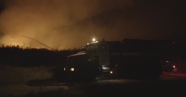 Пожарная машина с включенными фонарями. Пожарная машина на фоне сжигания травы на поле во время лесного пожара. Спасение и предотвращение стихийных бедствий . — стоковое видео