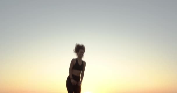 La femme sautant sur le trampoline sur un coucher de soleil . — Video