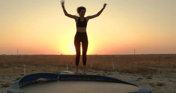 La femme sautant sur le trampoline sur un coucher de soleil . — Video