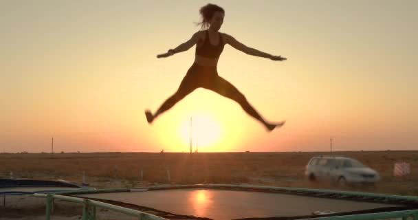 Žena skáče po trampolce při západu slunce. — Stock video