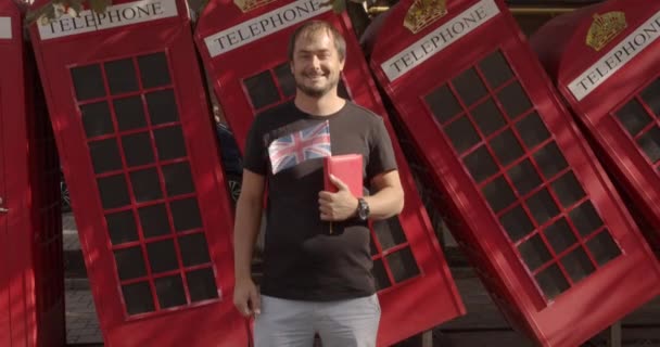 Un homme souriant levant les pouces, debout contre le téléphone britannique, étudiant l'anglais . — Video