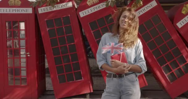 Η γυναίκα που κατέχει βρετανική σημαία και βιβλίο, εκπαίδευση στο εξωτερικό, μαθαίνοντας γλώσσα. — Αρχείο Βίντεο