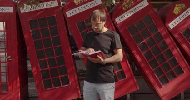 L'homme sur fond de téléphones britanniques rouges. Voyage, concept de lieux touristiques . — Video