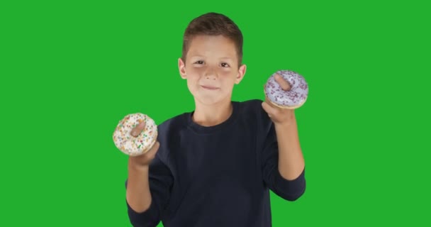 Detailní záběr. portrét legračního chlapa, jak se baví s barevnými koblihami na tváři. Výrazy, dietní koncept, barva pozadí. 4k. — Stock video