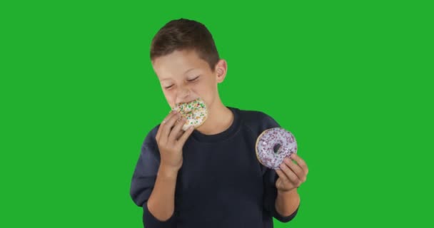 Κοντινό πλάνο. Πορτρέτο ενός αστείου που τρώει πολύχρωμα ντόνατς. Εκφράσεις, διαίτης, χρώμα φόντου. 4ια. — Αρχείο Βίντεο