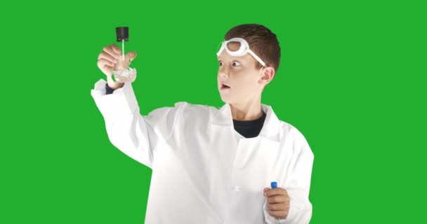 Porträt eines Schuljungen Chemiker bei einem Experiment in einem Kolben, auf grünem Hintergrund mit Chroma-Taste. — Stockvideo