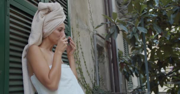 Young girl in a towel after a shower and drink a cup of coffee by the balcony in a cozy house. Relaxed morning home concept, lifestyle. — Stockvideo