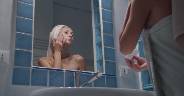 Jeune belle femme touchant la peau dans la salle de bain. routine de soins du matin . — Video