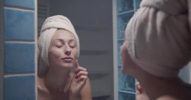 Genç ve güzel bir kadın banyoda tenine dokunuyor. Sabah cildi rutini.