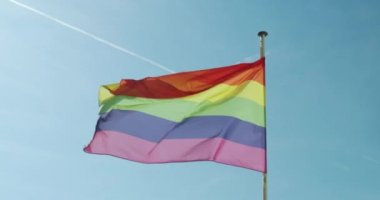 Büyük Gökkuşağı bayrağı gay gururu LGBTQ rüzgar tarafından mavi gökyüzüne karşı gelişiyor.