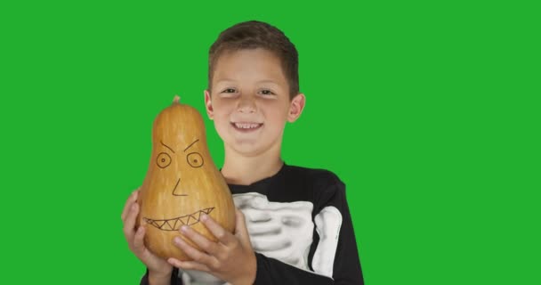 Niño vistiendo traje con un pumkin sonriendo para la fiesta de Halloween contra croma clave fondo de pantalla verde . — Vídeo de stock