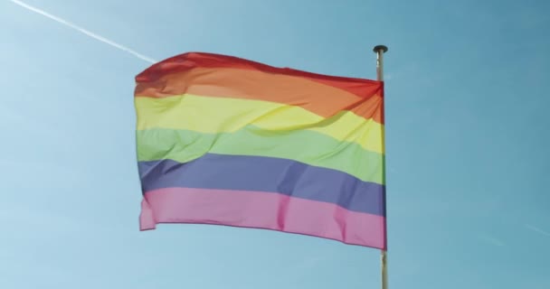 Big Rainbow flagga gay stolthet HBTQ utvecklas av vinden mot den blå himlen. — Stockvideo