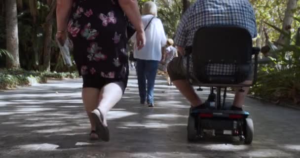 Barcelone, Espagne - 15 octobre 2019 : Scooter motorisé pour personnes âgées ou handicapées.Une femme escorte un homme en fauteuil roulant mécanisé . — Video