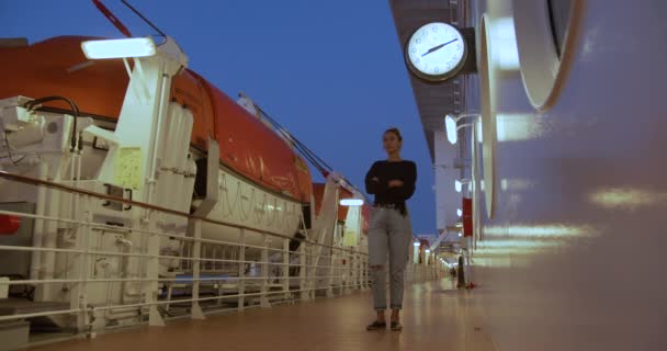 Una chica está esperando una reunión en la cubierta de un crucero bajo el reloj . — Vídeos de Stock