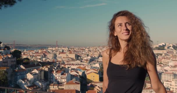 Jolie fille sur une plate-forme d'observation examine la ville et se baigne au soleil . — Video
