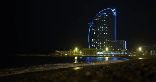 Barcelona, Spanyolország - 2019. október 15.: Barcelona, Spanyolország. Kilátás a szálloda-vitorla a tengerparton Barceloneta éjszaka, Timelapse. — Stock videók