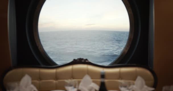 Uitzicht door een patrijspoort op een stormachtige zee met golven op cruiseschip in restaurante. — Stockvideo