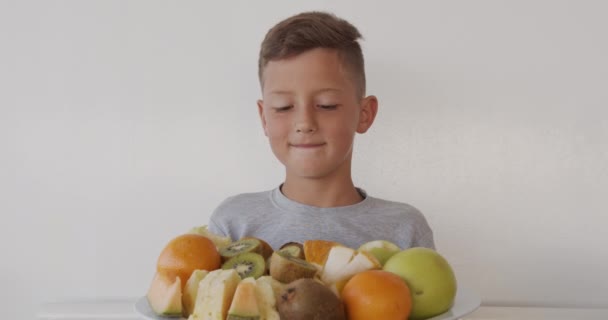 Słodki chłopiec jedzący dojrzałe soczyste owoce. Zbliżenie. — Wideo stockowe