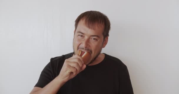 Uomo felice mordere delizioso hot-dog e sorridente . — Video Stock