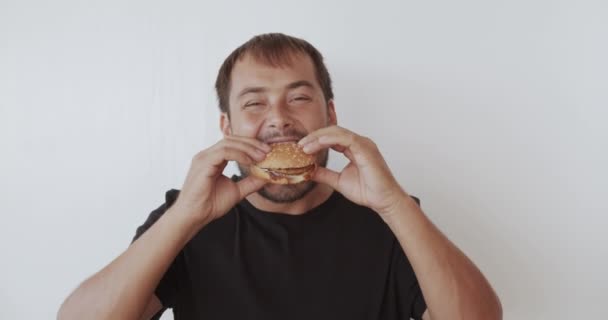 Homem feliz comendo saboroso hambúrguer fast food . — Vídeo de Stock