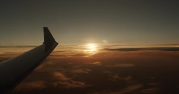 Vleugel van een vliegtuig dat boven de wolken vliegt met zonsondergang. Zicht vanuit het raam van het vliegtuig. — Stockvideo