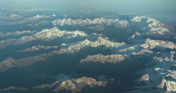 Hermosa vista a través de la ventana del avión, avión volando por encima de las montañas con nubes. — Vídeos de Stock