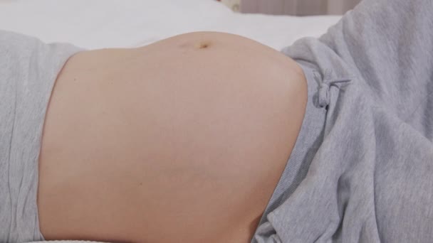 Cerca de la mujer embarazada jugando con el bebé pateando desde el interior del útero . — Vídeos de Stock