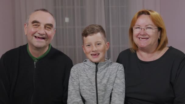 Feliz abuelo y abuela abrazan nieto, niño, niño. Todos juntos sonriendo a la cámara . — Vídeo de stock