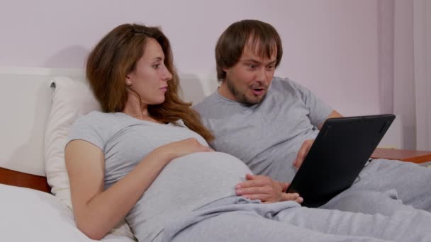 Boldog férfi és a terhes felesége okostelefonnal otthon. Terhesség, technológia és emberek fogalma. — Stock videók