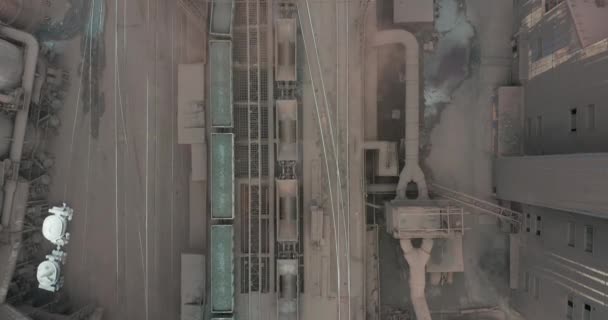 AERIAL TOP DOWN:産業鉄道駅を出る貨物列車ワゴンの上を飛ぶ. — ストック動画