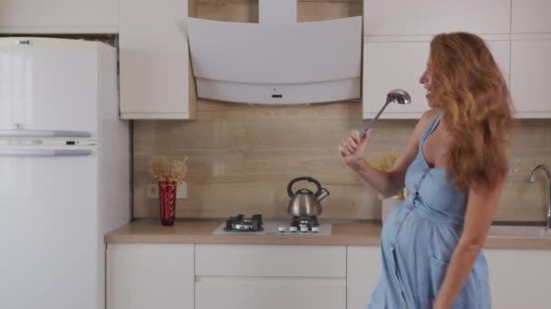 Mamá embarazada escuchando música y bailando en casa en la cocina. Retrato Mujer de pie en la cocina Día soleado . — Vídeo de stock