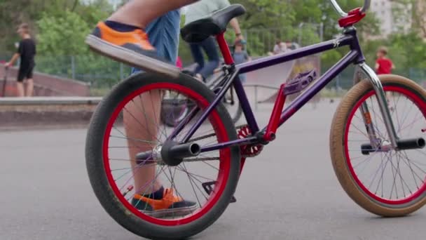 MOCIÓN LENTA: Bmx extremo irreconocible ciclista montar en bicicleta en el parque soleado en el hermoso verano . — Vídeo de stock