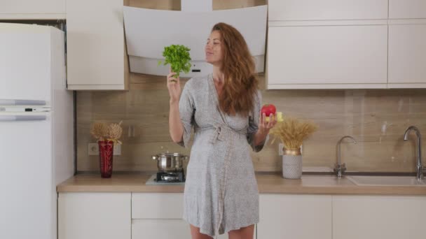 Mujer embarazada mezclando ensalada verde fresca en la cocina. Primer plano. . — Vídeo de stock