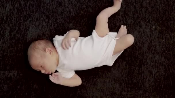 Potret seorang bayi yang baru lahir terletak pada seprai hitam dan membuka mulutnya. Saat-saat pertama kehidupan. Close-up of newborn baby face portrait. — Stok Video