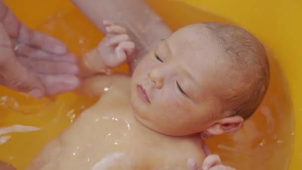 Hoge hoek uitzicht van ouders baden hun pasgeboren baby meisje. — Stockvideo