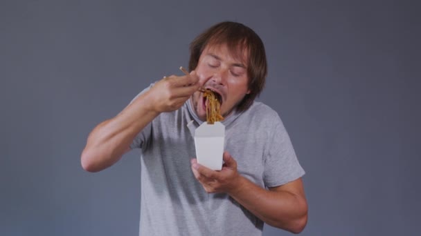 A férfias élvezet ételt eszik. Mosolygó férfiak fehér dobozban kínai tésztával.. — Stock videók