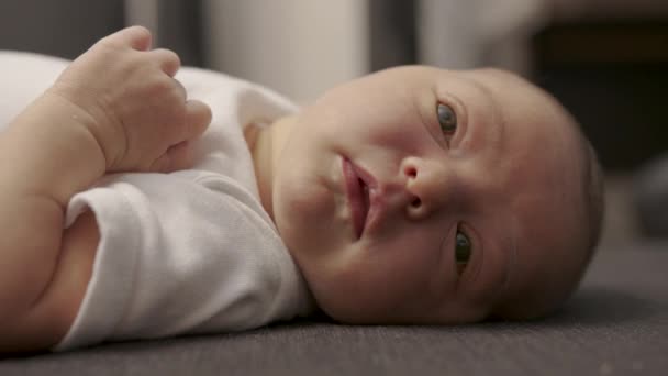 Nahaufnahme des Gesichts eines Neugeborenen in den ersten Tagen, das aufwacht und seine Augen öffnet. Ein neugeborenes Baby Grimassen durch einen Traum. Neugeborenes in den ersten Minuten des Lebens. — Stockvideo